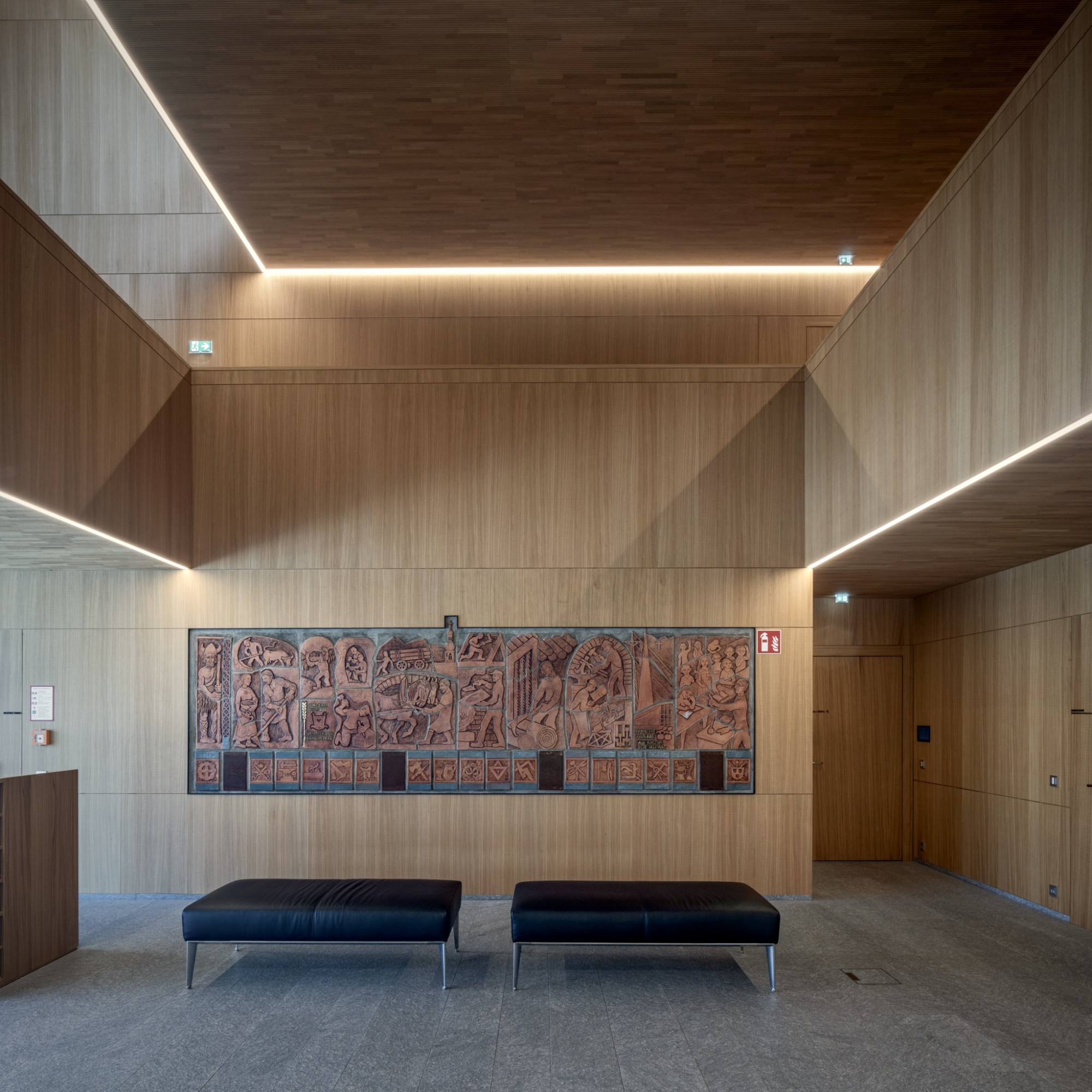 Gemeindezentrum Haiming, Foyer mit Holzvertäfelung und historischem Terrakotta-Wandrelief