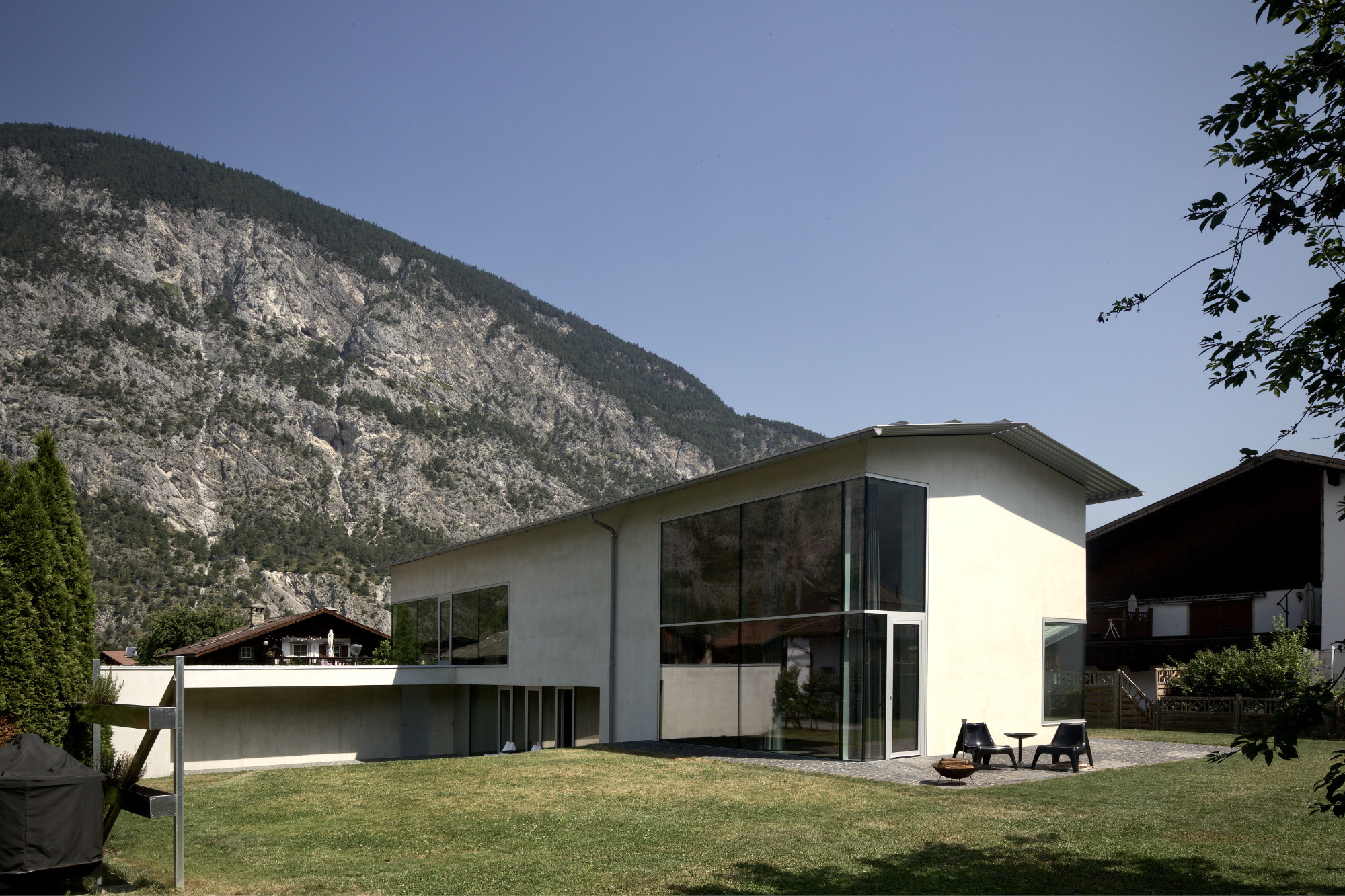 HannesnHaus, Silz, Gebäudeansicht vor Bergkulisse mit Betonfassade und raumhoher Eckverglasung